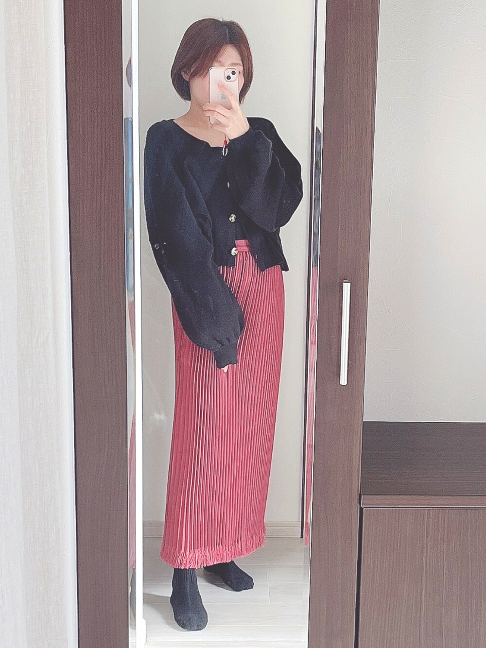 ブラック系のカーディガン/ボレロ、パープル系のスカートを着用したレディースの冬コーディネートの1枚目の写真