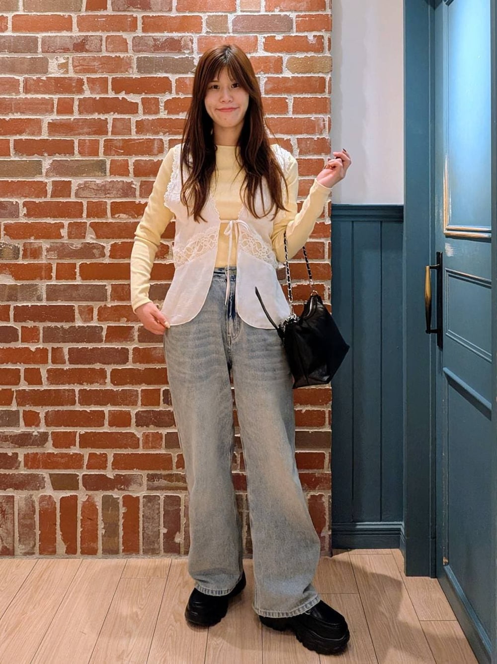 ブルー系のデニムパンツ、ブラック系のショルダーバッグ、ブラック系のローファーを着用したレディースの冬コーディネートの1枚目の写真