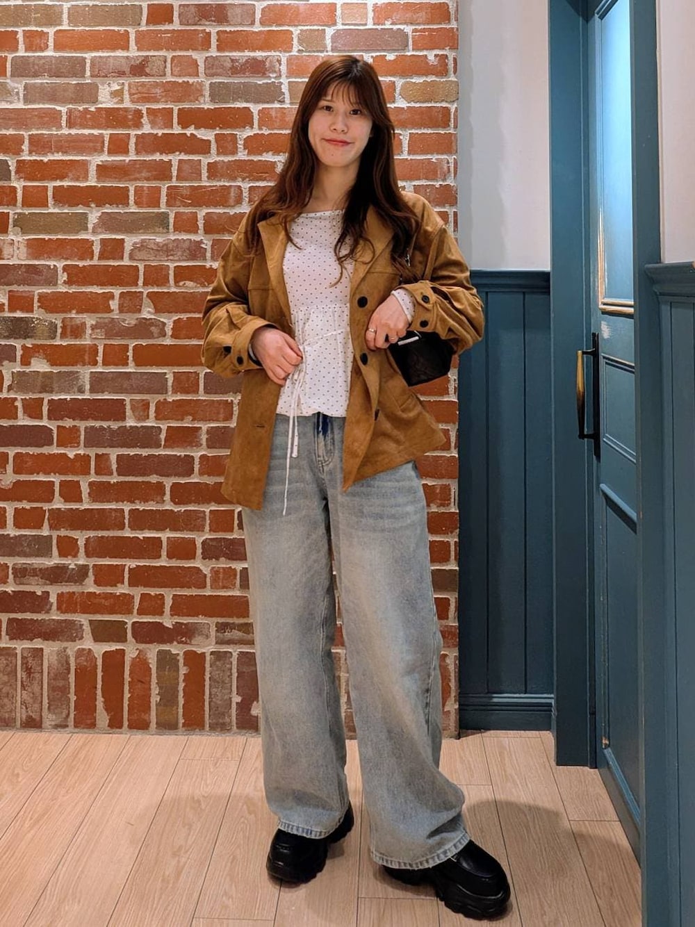 ブルー系のデニムパンツ、ブラック系のショルダーバッグ、ブラック系のローファーを着用したレディースの冬コーディネートの1枚目の写真