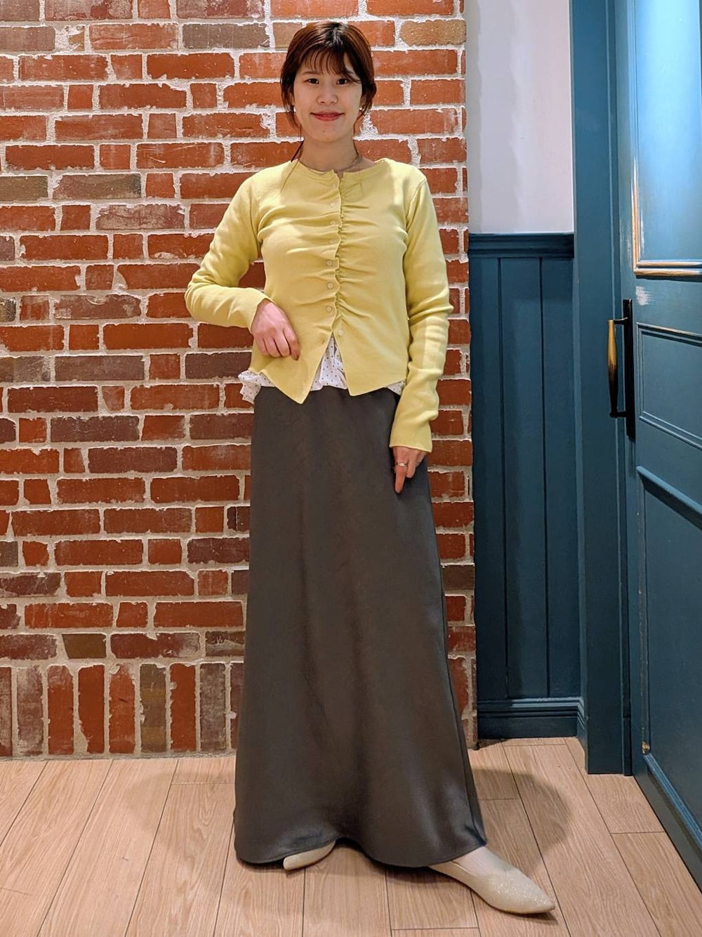 グレー系のスカート、ホワイト系のパンプス、ホワイト系のTシャツ/カットソーを着用したレディースの春コーディネートの1枚目の写真