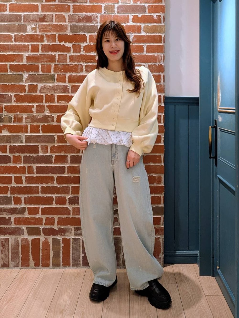 ブルー系のデニムパンツ、ブラック系のローファー、イエロー系のスウェットを着用したレディースの冬コーディネートの1枚目の写真