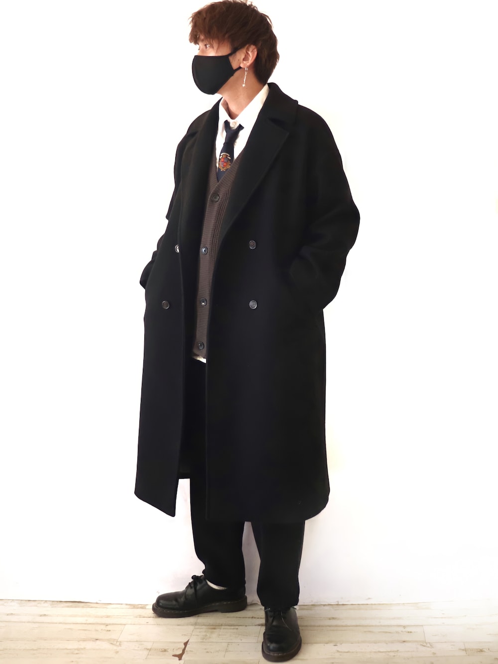 ブラック系のチェスターコート、グレー系のカーディガン/ボレロ、ホワイト系のシャツ/ブラウスを着用したメンズの冬コーディネートの1枚目の写真