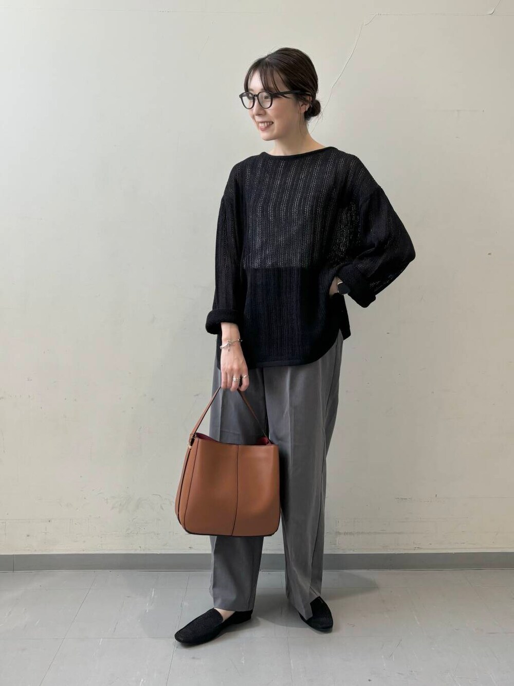 ブラウン系のハンドバッグ、グレー系のその他パンツ、ブラック系のニット/セーターを着用したレディースの夏コーディネートの1枚目の写真