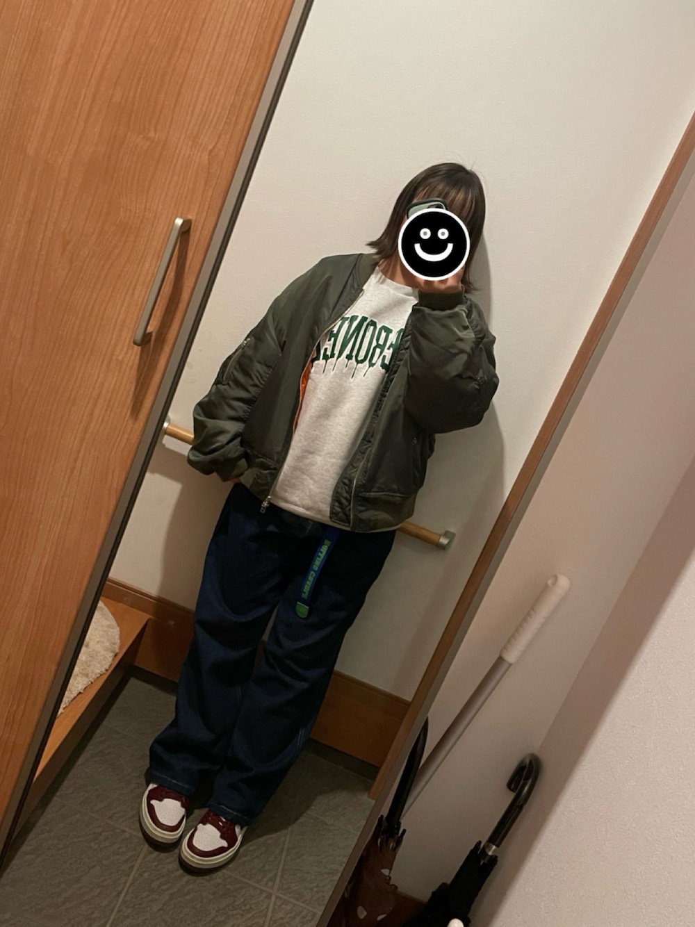 ブルー系のデニムパンツ、グレー系のスウェット、グリーン系のブルゾンを着用したレディースの冬コーディネートの1枚目の写真