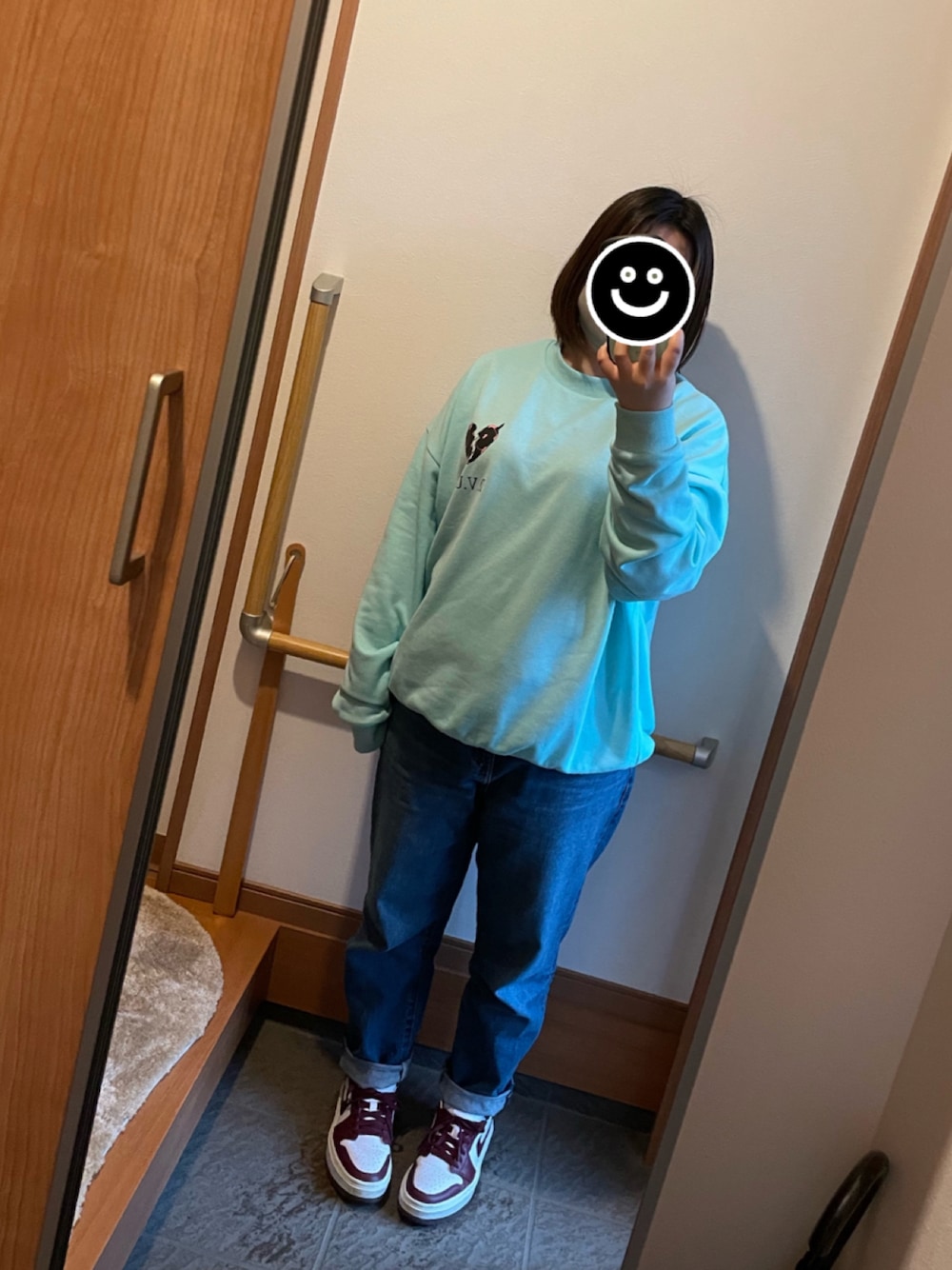 グリーン系のスウェット、ブルー系のデニムパンツ、ホワイト系のスニーカーを着用したレディースの春コーディネートの1枚目の写真