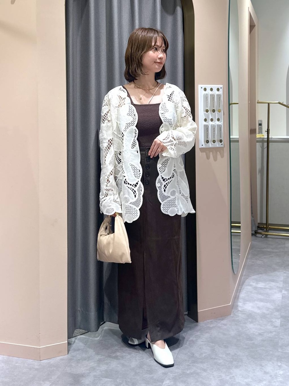 ベージュ系のハンドバッグ、ブラウン系のニット/セーター、ホワイト系のシャツ/ブラウスを着用したレディースの秋コーディネートの1枚目の写真
