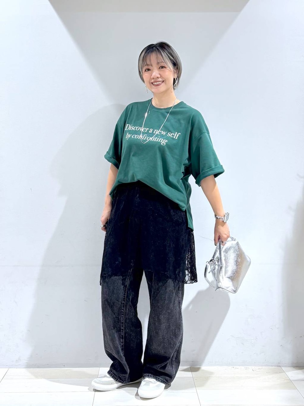 シルバー系のショルダーバッグ、ホワイト系のスニーカー、ブラック系のスカートを着用したレディースの秋コーディネートの1枚目の写真