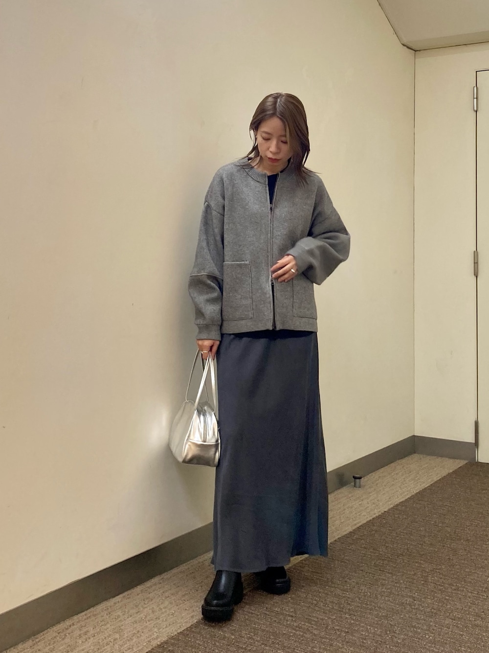 グレー系のニット/セーター、ブラック系のTシャツ/カットソー、グレー系のスカートを着用したレディースの秋コーディネートの1枚目の写真