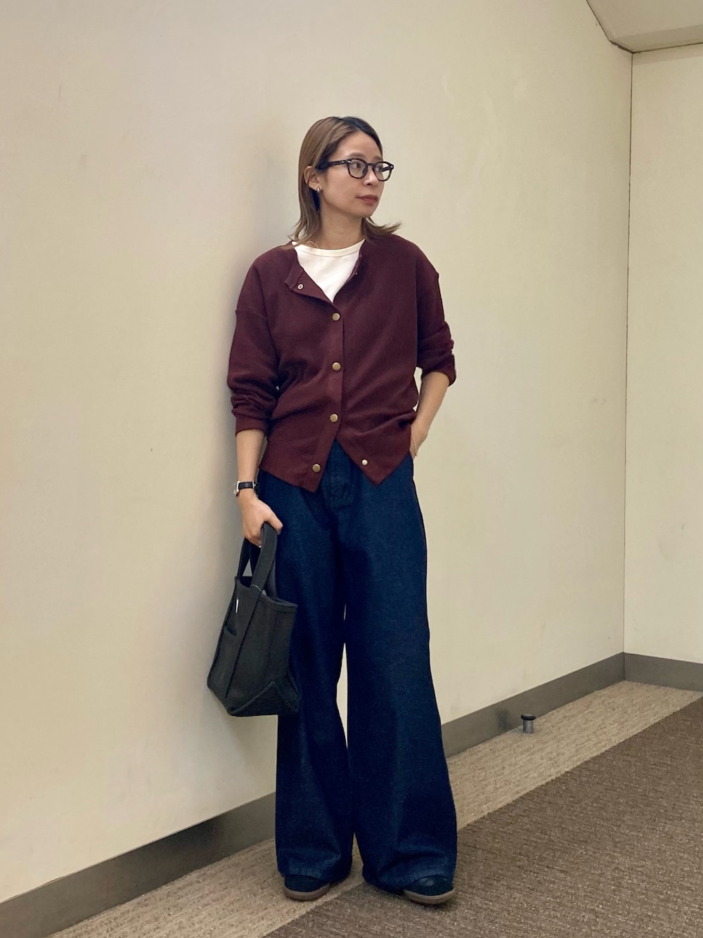 レッド系のカーディガン/ボレロ、ブルー系のデニムパンツ、グレー系のトートバッグを着用したレディースの秋コーディネートの1枚目の写真