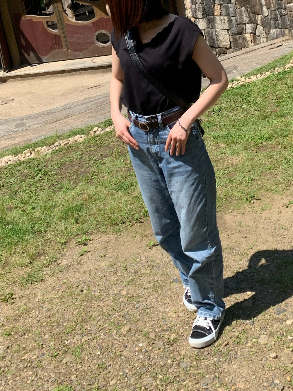 ブラック系のトップス、ブルー系のデニムパンツ、ブラック系のスニーカーを着用したレディースの春コーディネートの1枚目の写真