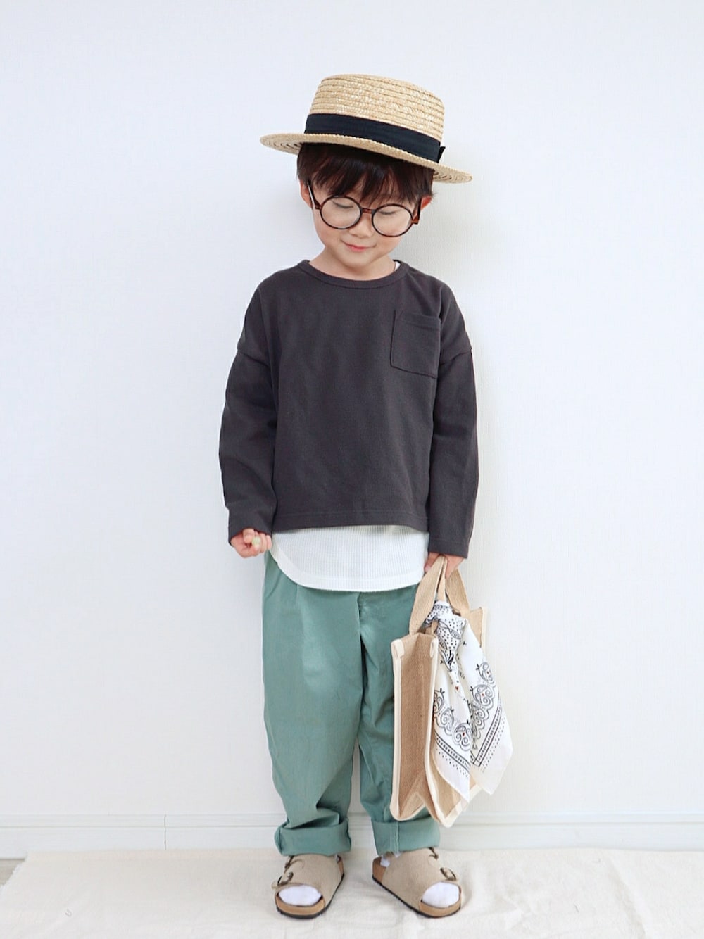 ブラック系のTシャツ/カットソー、グリーン系のその他パンツ、ベージュ系のトートバッグを着用したキッズの春コーディネートの1枚目の写真