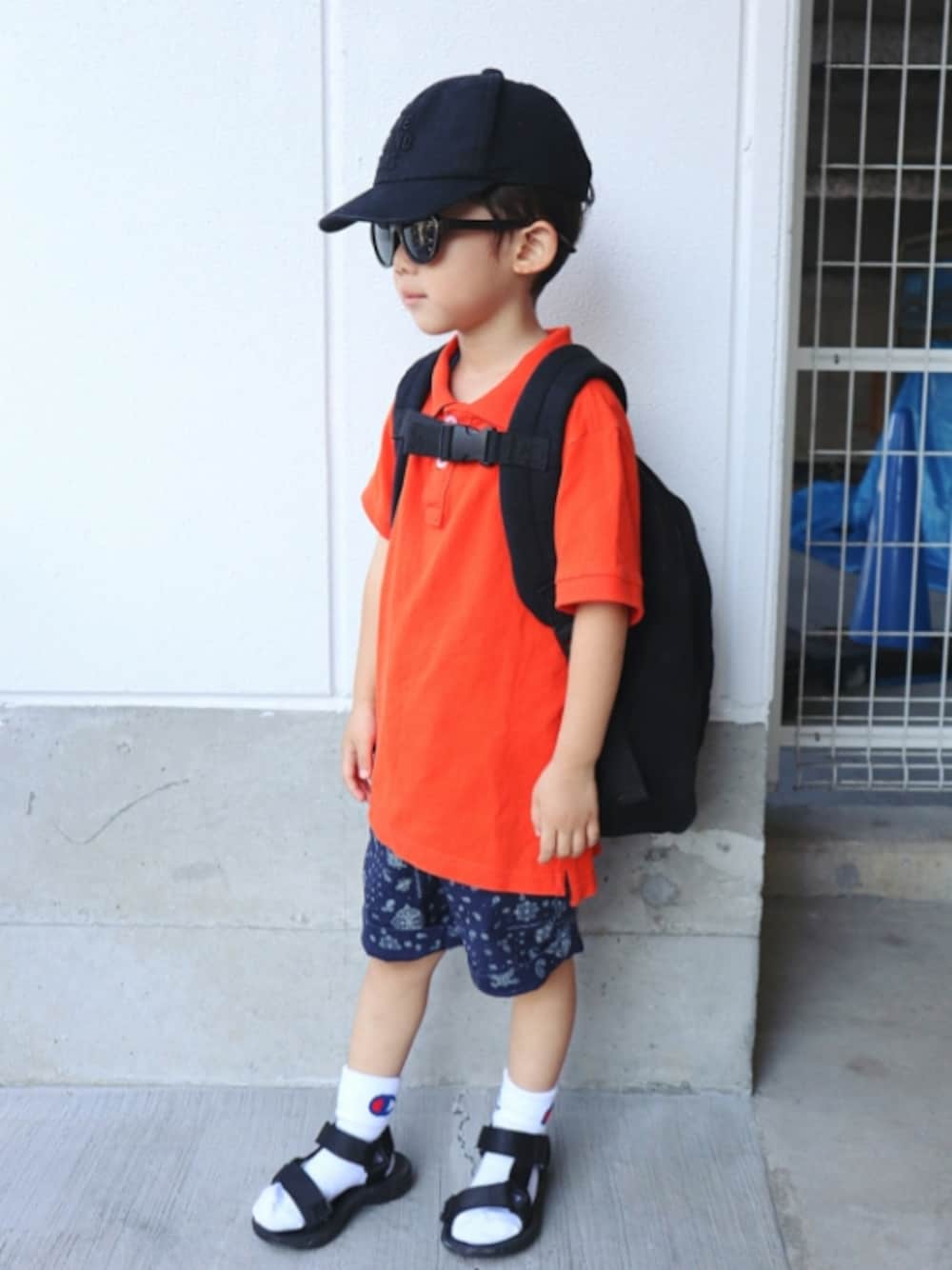 オレンジ系のポロシャツ、ブラック系のバックパック/リュック、ブルー系のその他パンツを着用したキッズの夏コーディネートの1枚目の写真