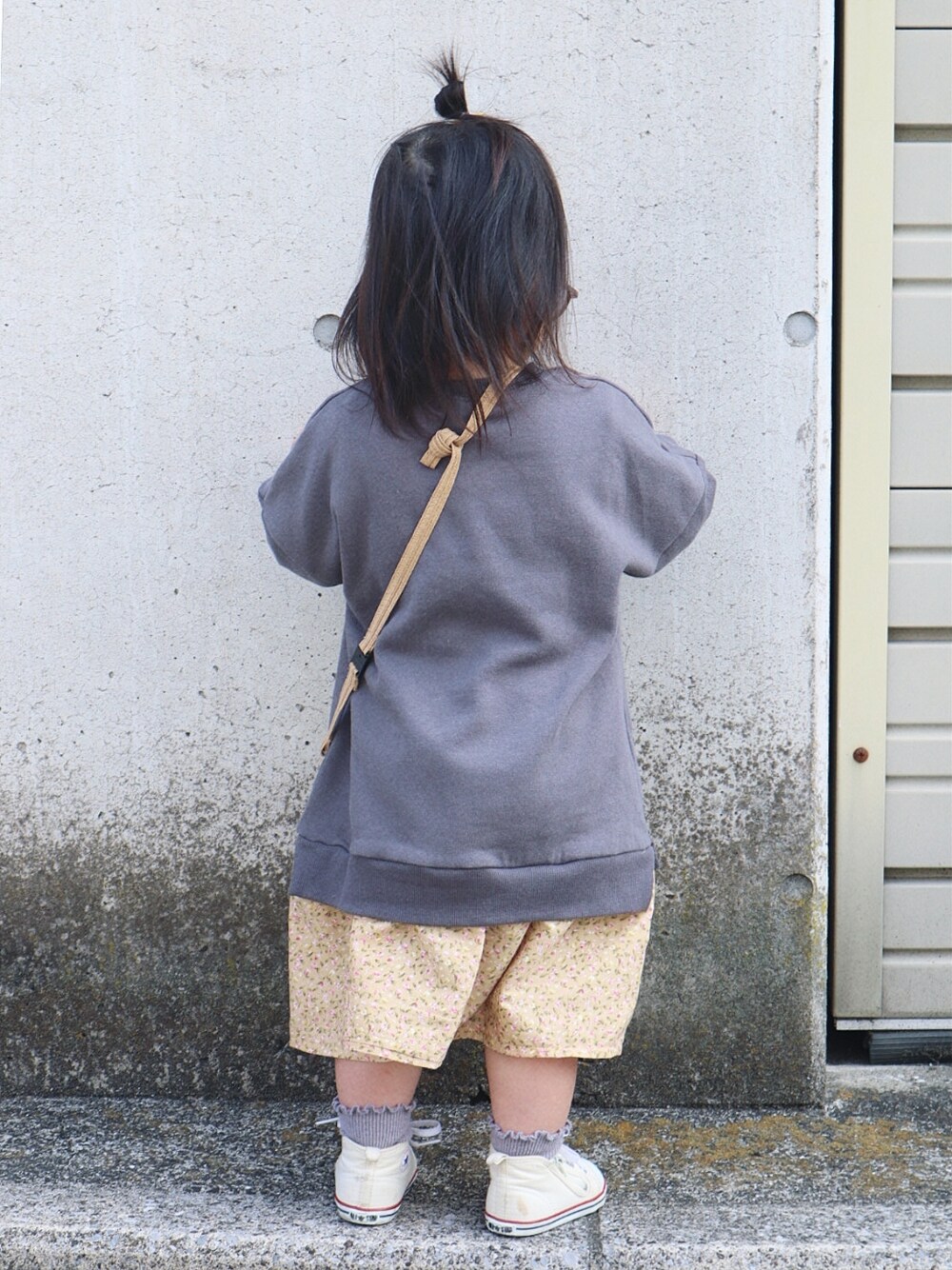 グレー系のワンピース、ベージュ系のショルダーバッグ、ホワイト系のスニーカーを着用したキッズの春コーディネートの3枚目の写真