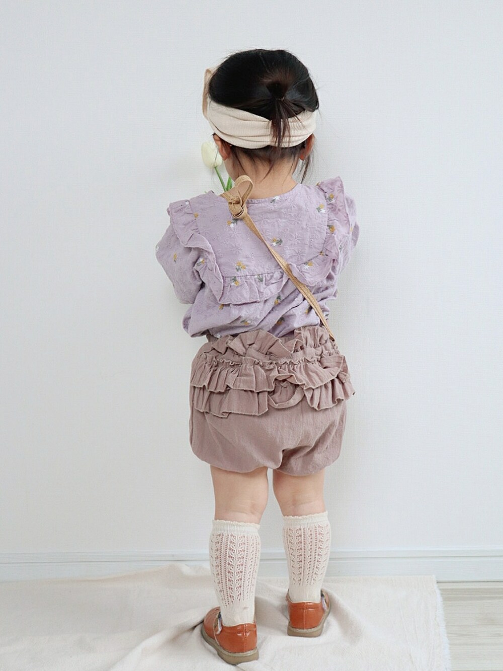 パープル系のシャツ/ブラウス、ベージュ系のパンツ、ベージュ系のショルダーバッグを着用したキッズの春コーディネートの3枚目の写真