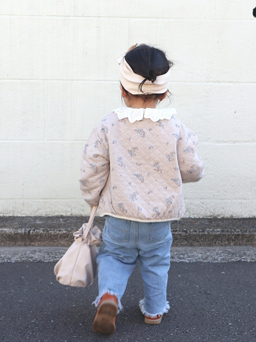 ベージュ系のノーカラージャケット、ホワイト系のトートバッグ、ブルー系のデニムパンツを着用したキッズの春コーディネートの3枚目の写真