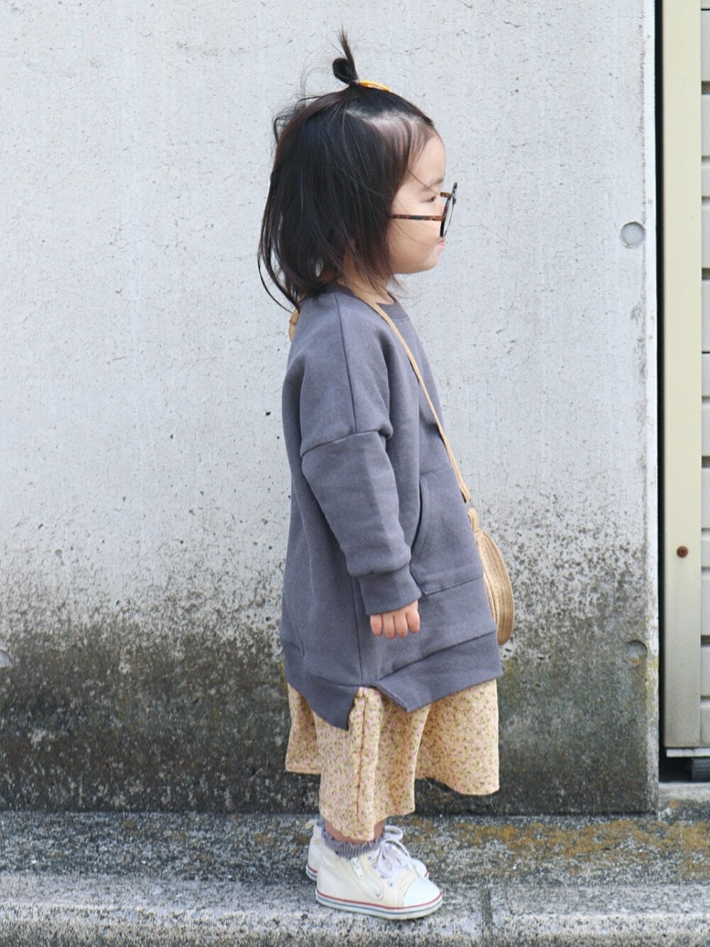 グレー系のワンピース、ベージュ系のショルダーバッグ、ホワイト系のスニーカーを着用したキッズの春コーディネートの2枚目の写真