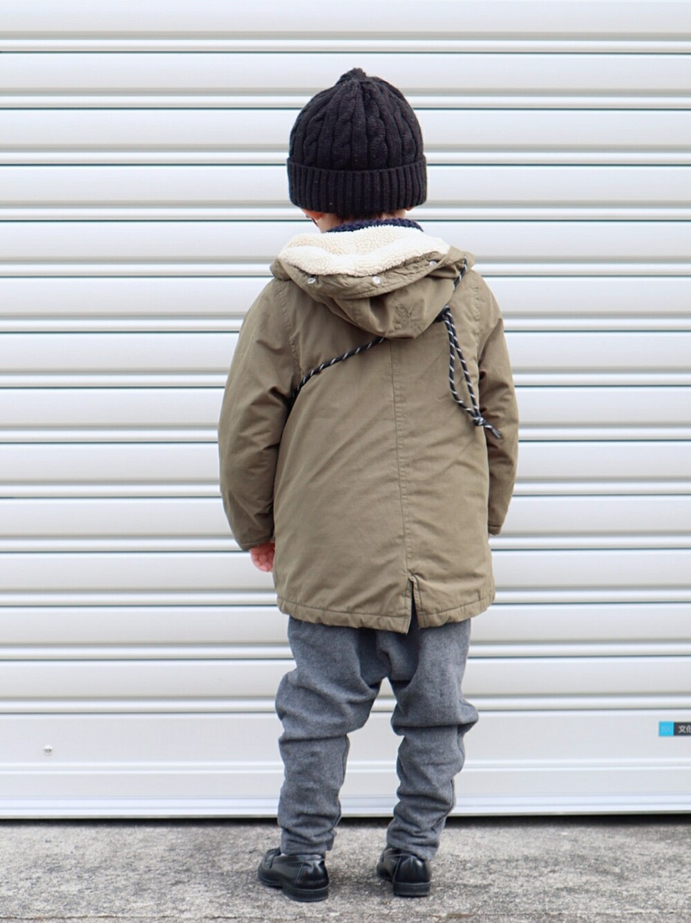 グリーン系のモッズコート、レッド系のベスト、グレー系のスウェットパンツを着用したキッズの冬コーディネートの2枚目の写真