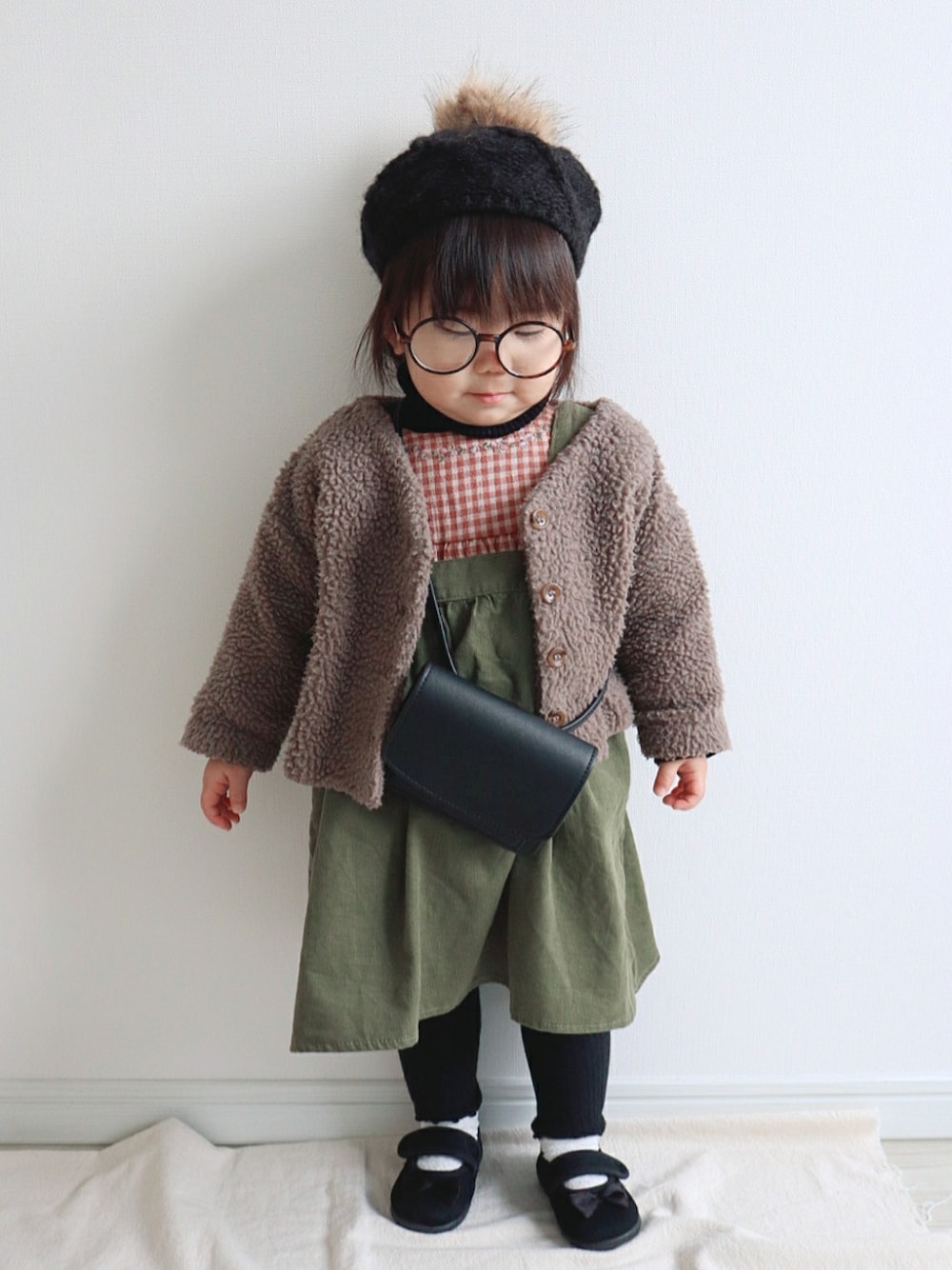ブラウン系のカーディガン/ボレロ、オレンジ系のシャツ/ブラウス、グリーン系のジャンパースカートを着用したキッズの冬コーディネートの3枚目の写真