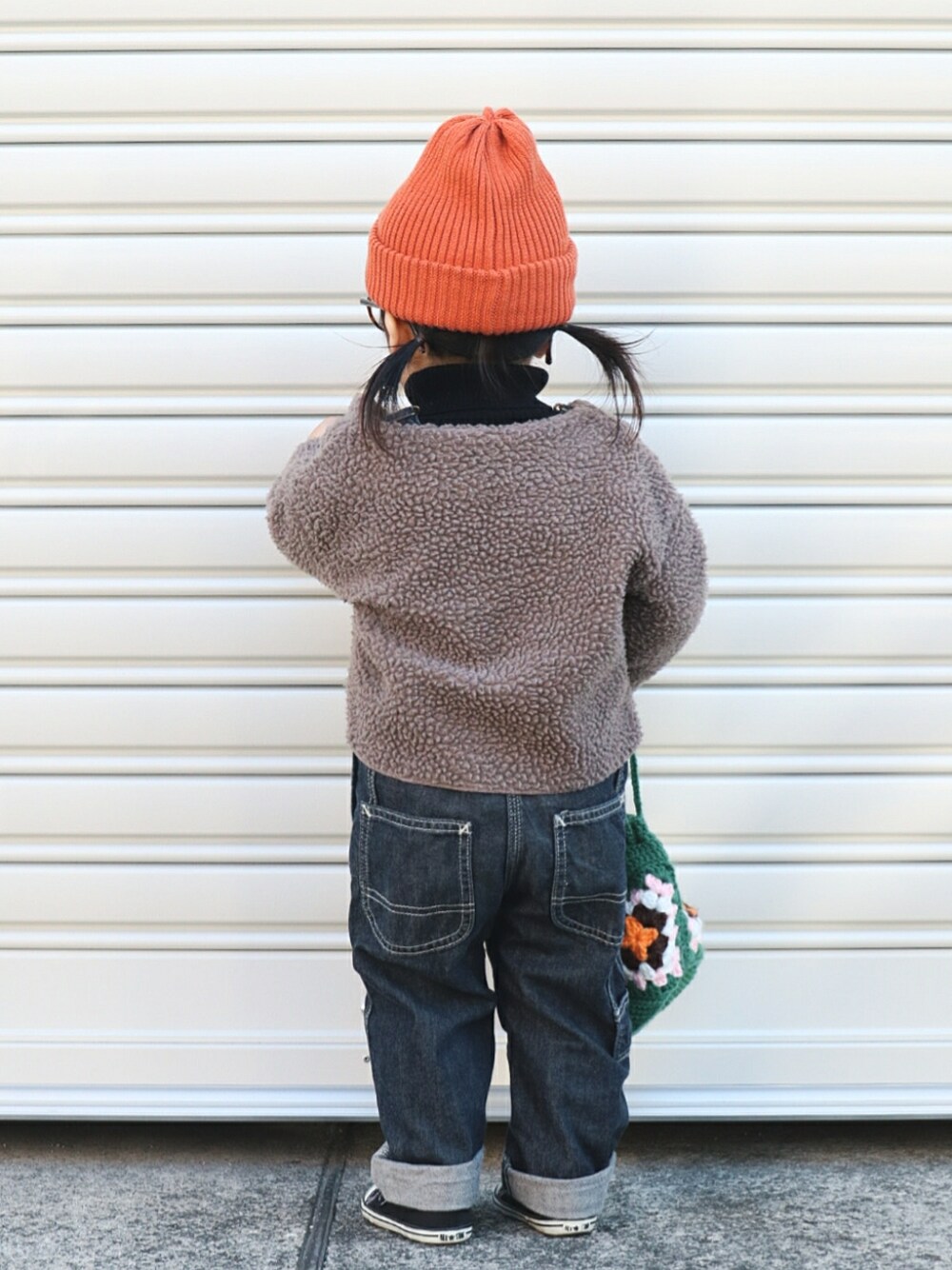 ブラウン系のカーディガン/ボレロ、ブラック系のニット/セーター、ブルー系のサロペット/オーバーオールを着用したキッズの冬コーディネートの4枚目の写真