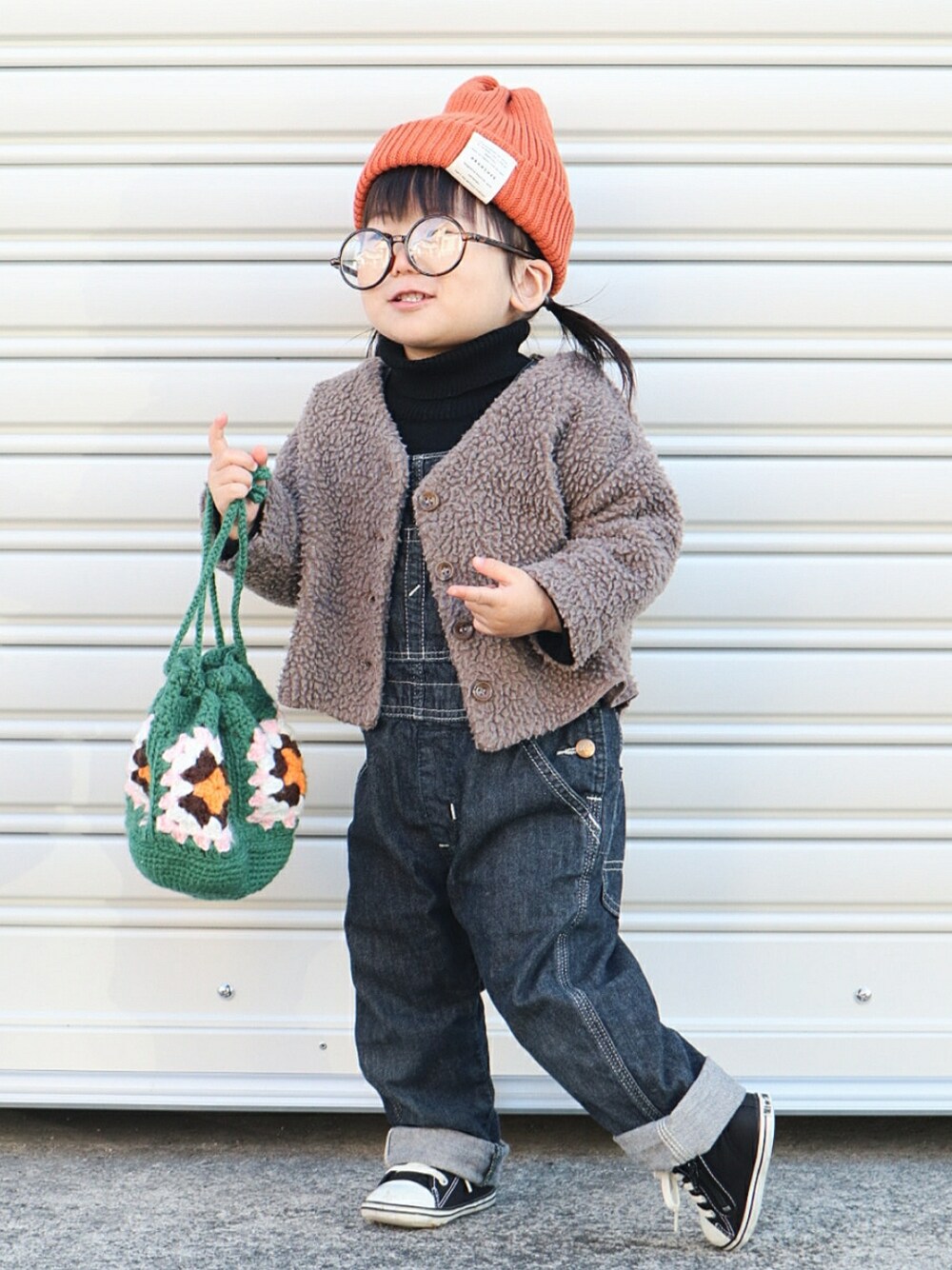 ブラウン系のカーディガン/ボレロ、ブラック系のニット/セーター、ブルー系のサロペット/オーバーオールを着用したキッズの冬コーディネートの3枚目の写真