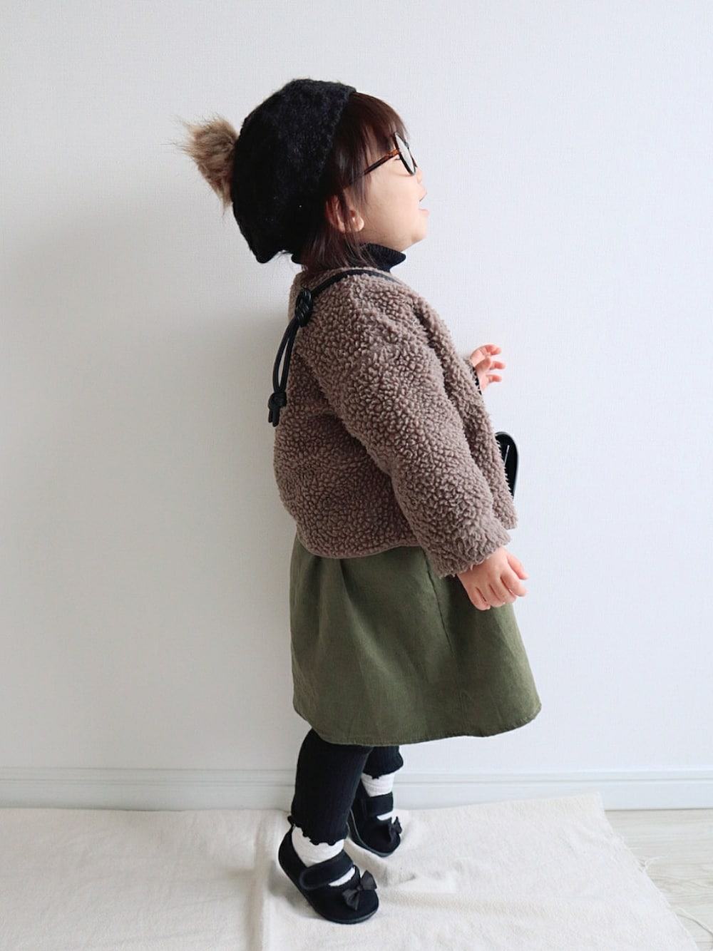 ブラウン系のカーディガン/ボレロ、オレンジ系のシャツ/ブラウス、グリーン系のジャンパースカートを着用したキッズの冬コーディネートの2枚目の写真