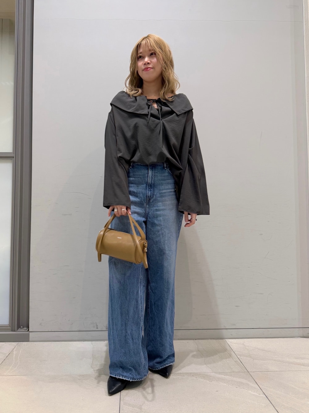 ブルー系のデニムパンツ、オレンジ系のショルダーバッグ、グレー系のシャツ/ブラウスを着用したレディースの春コーディネートの1枚目の写真