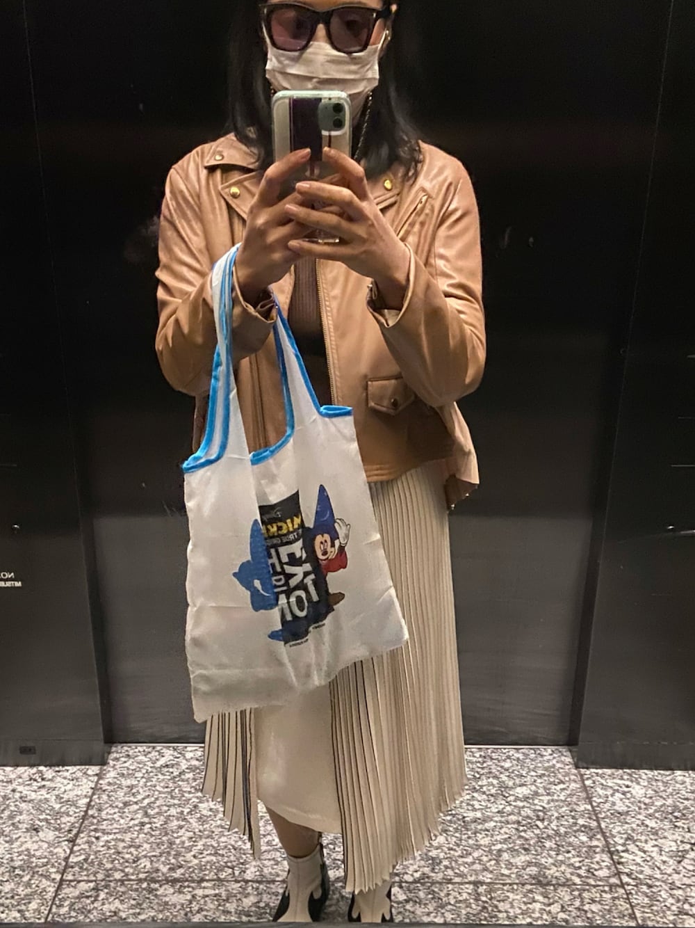 「不審者、CELINE、サングラス、Titilate valet、ライダース、NINE、白プリーツスカート、TOGA PULLA、ウエスタンブーツ、ミッキー、エコバッグ」｜「MICKEY MOUSEのアイテム（エコバッグ/サブバッグ、ホワイト系）」を使った、小池さん（レディース・159cm）の秋コーディネートの1枚目の写真