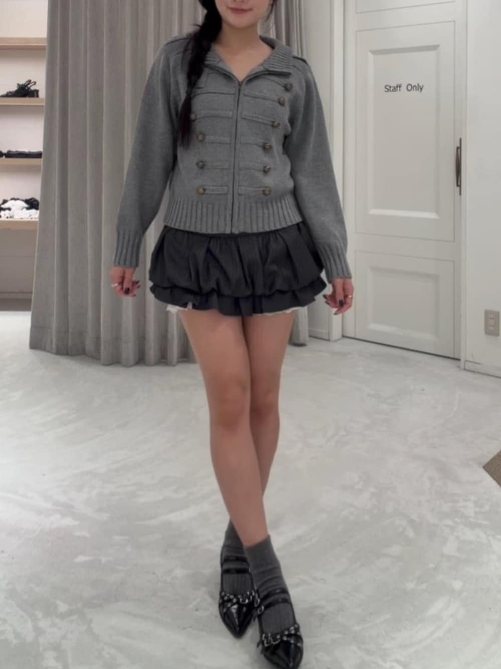 ブラック系のパンプス、ブラック系のスカート、グレー系のニット/セーターを着用したレディースの秋コーディネートの1枚目の写真