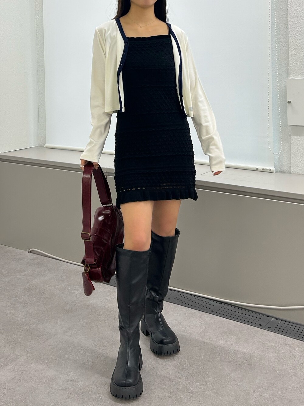 ブラック系のワンピース、レッド系のショルダーバッグ、ホワイト系のカーディガン/ボレロを着用したレディースの冬コーディネートの1枚目の写真