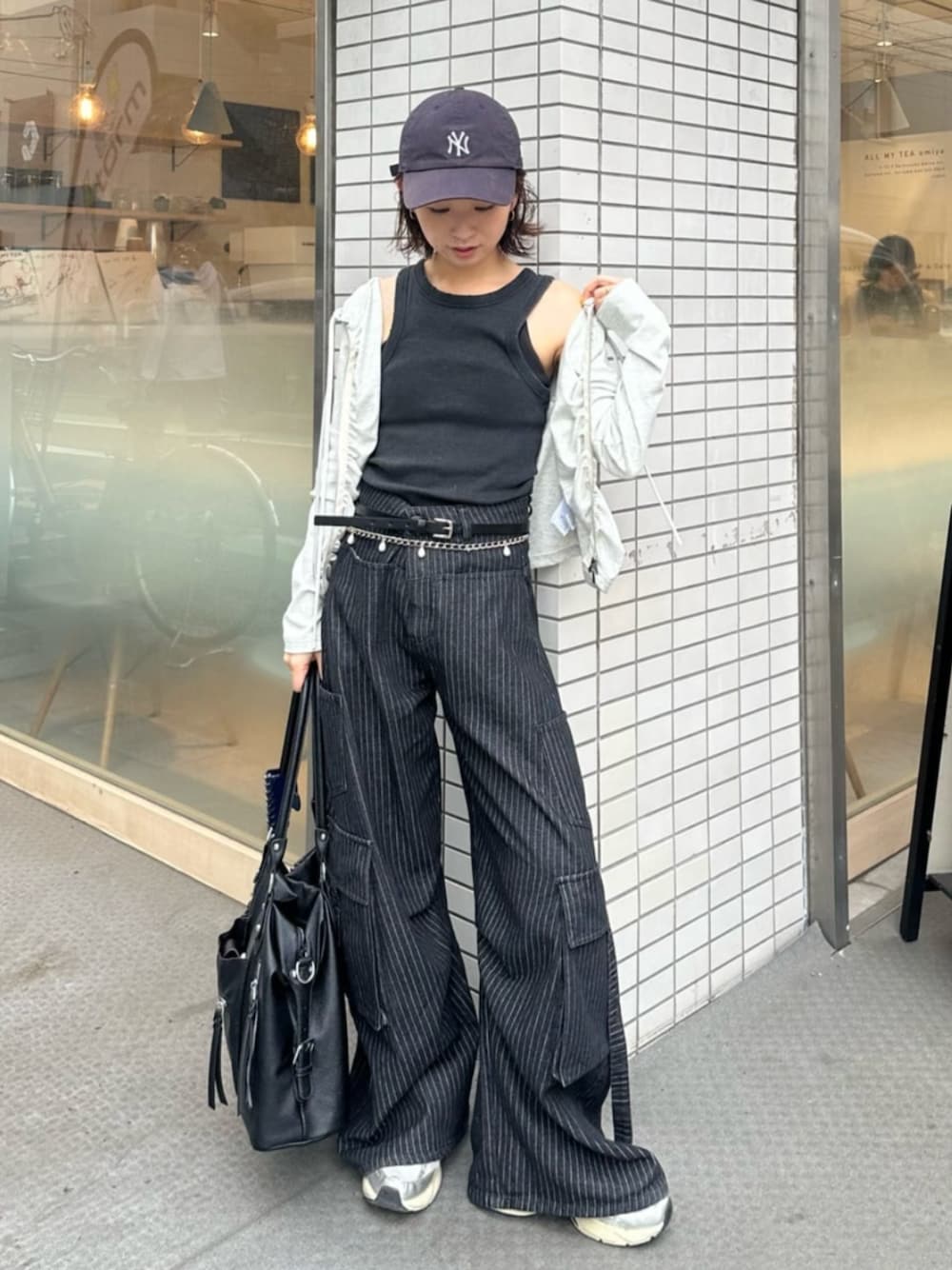 グレー系のパーカー、ブラック系のデニムパンツ、ブラック系のショルダーバッグを着用したレディースの夏コーディネートの1枚目の写真