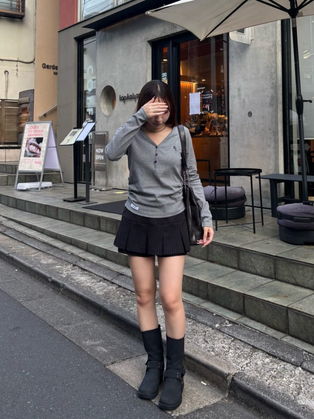 ブラック系のスカート、ブラック系のブーツ、ブラック系のトートバッグを着用したレディースの夏コーディネートの1枚目の写真