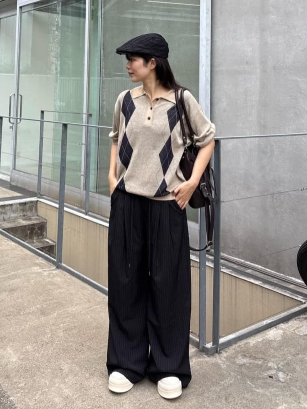 ベージュ系のニット/セーター、ブルー系のスラックス、ホワイト系のスニーカーを着用したレディースの夏コーディネートの1枚目の写真