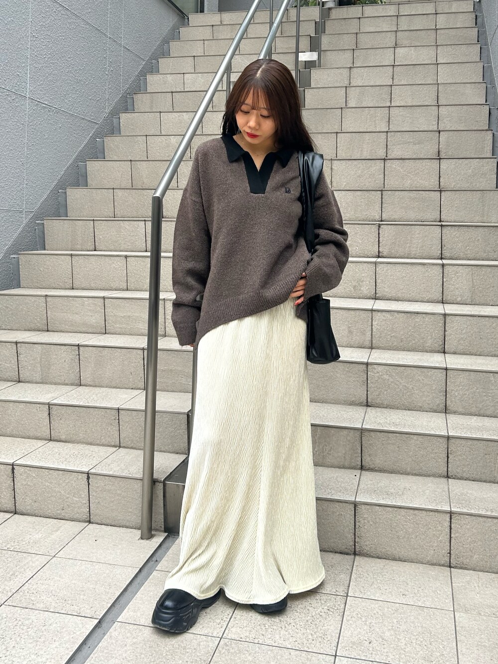 ブラウン系のニット/セーター、ベージュ系のスカート、ブラック系のハンドバッグを着用したレディースの秋コーディネートの1枚目の写真