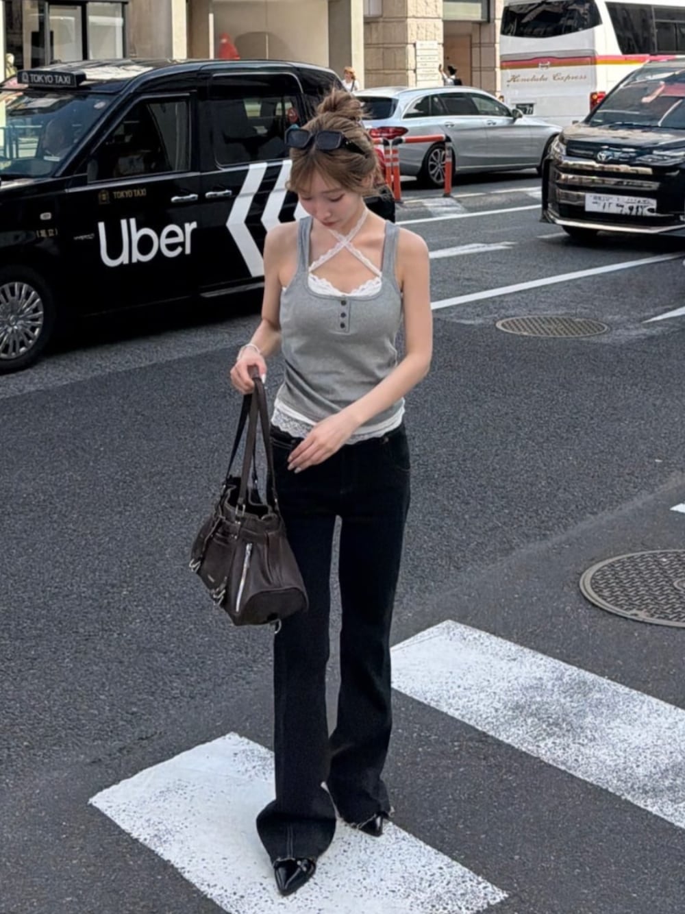 ブラウン系のショルダーバッグ、グレー系のTシャツ/カットソー、ブラック系のデニムパンツを着用したレディースの夏コーディネートの1枚目の写真