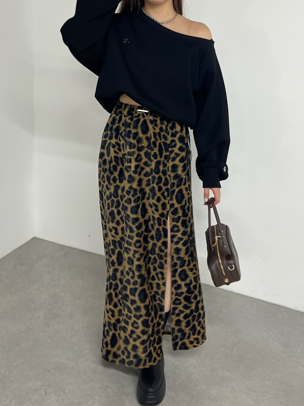 ブラック系のスウェット、ベージュ系のスカート、ブラウン系のボストンバッグを着用したレディースの秋コーディネートの1枚目の写真