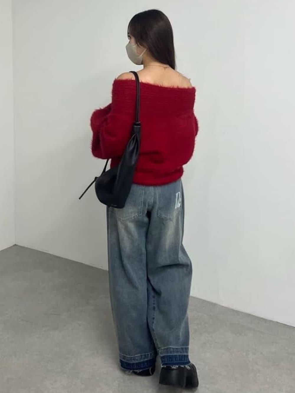 グレー系のニット/セーター、ブルー系のデニムパンツ、ブラック系のバックパック/リュックを着用したレディースの冬コーディネートの1枚目の写真