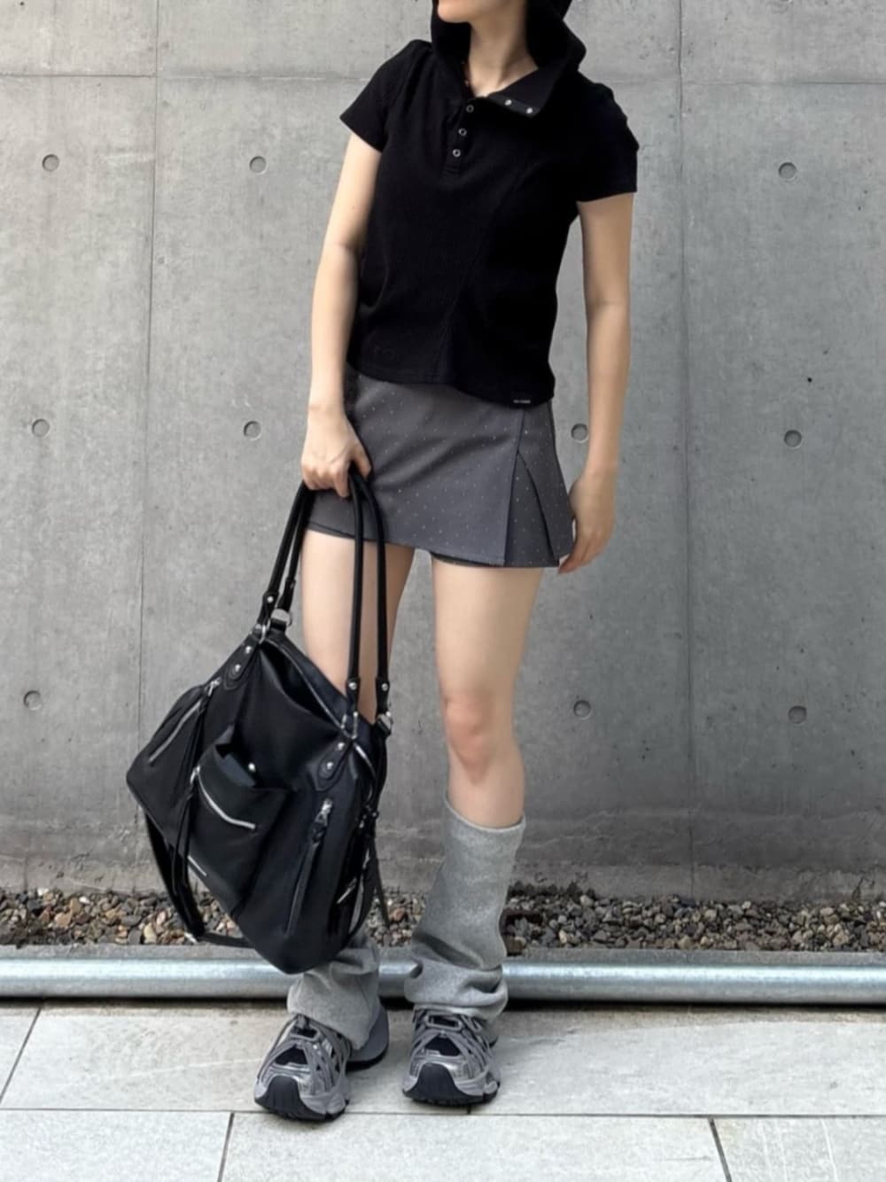 ブラック系のショルダーバッグ、ブラック系のTシャツ/カットソー、グレー系のスカートを着用したレディースの春コーディネートの1枚目の写真