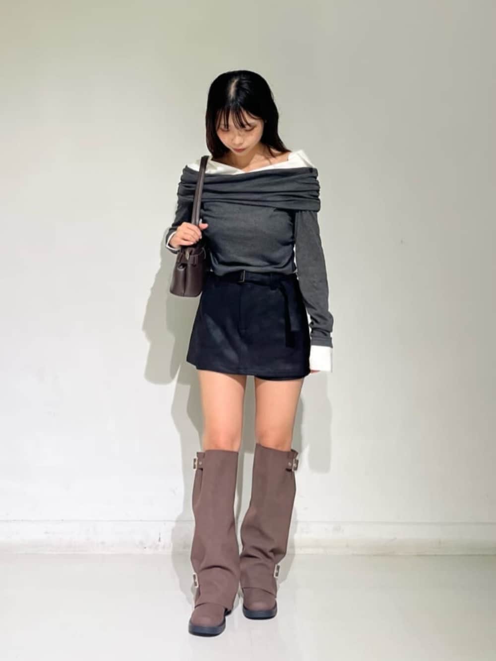 グレー系のTシャツ/カットソー、ブラック系のスカート、ブラウン系のブーツを着用したレディースの秋コーディネートの1枚目の写真