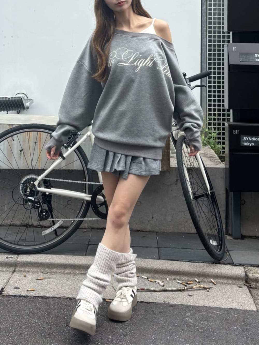 グレー系のスウェット、グレー系のスカート、ホワイト系のレッグウォーマーを着用したレディースの秋コーディネートの1枚目の写真