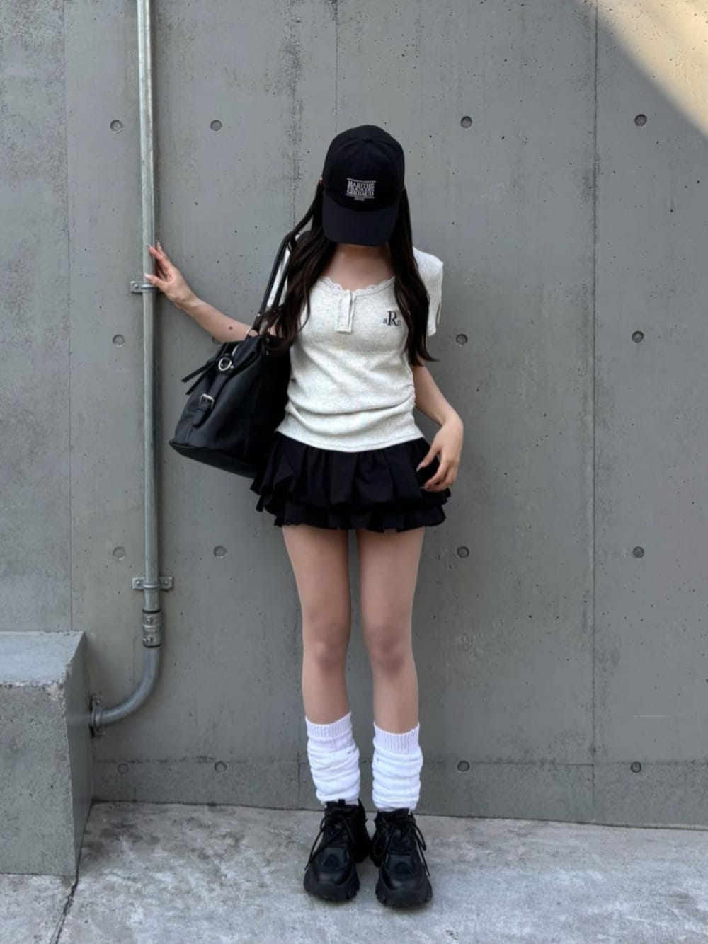 ブラック系のスカート、ホワイト系のTシャツ/カットソーを着用したレディースの春コーディネートの1枚目の写真