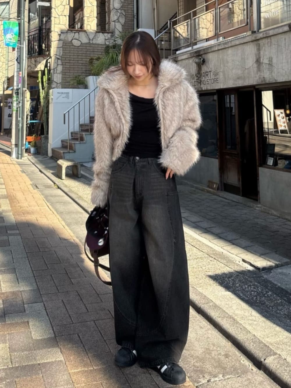 ブラック系のデニムパンツを着用したレディースの冬コーディネートの1枚目の写真