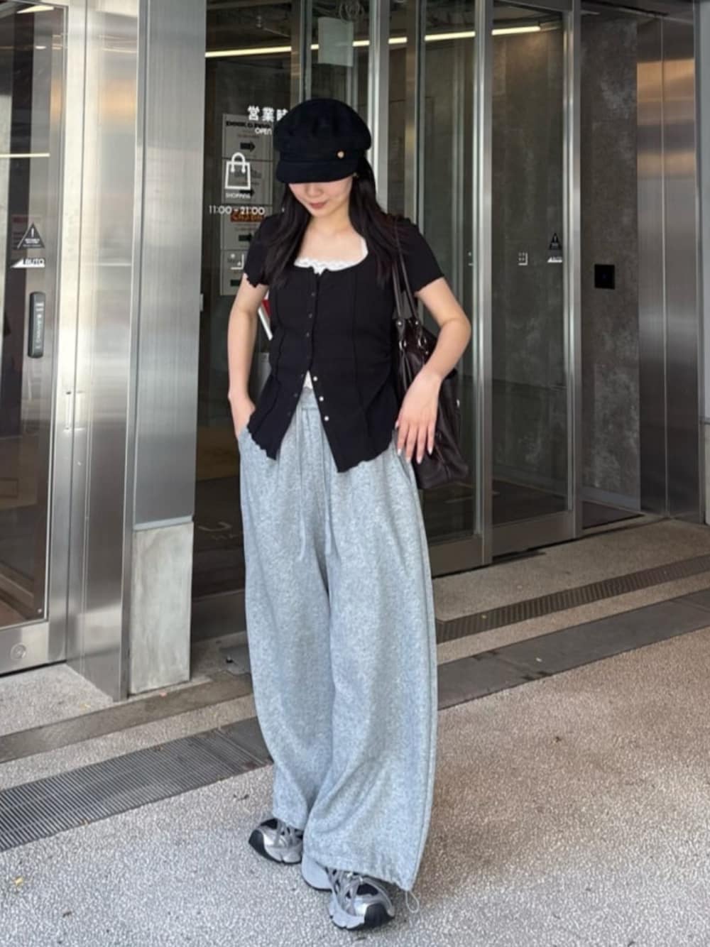 グレー系のスウェットパンツ、シルバー系のスニーカー、ブラック系のTシャツ/カットソーを着用したレディースの春コーディネートの1枚目の写真