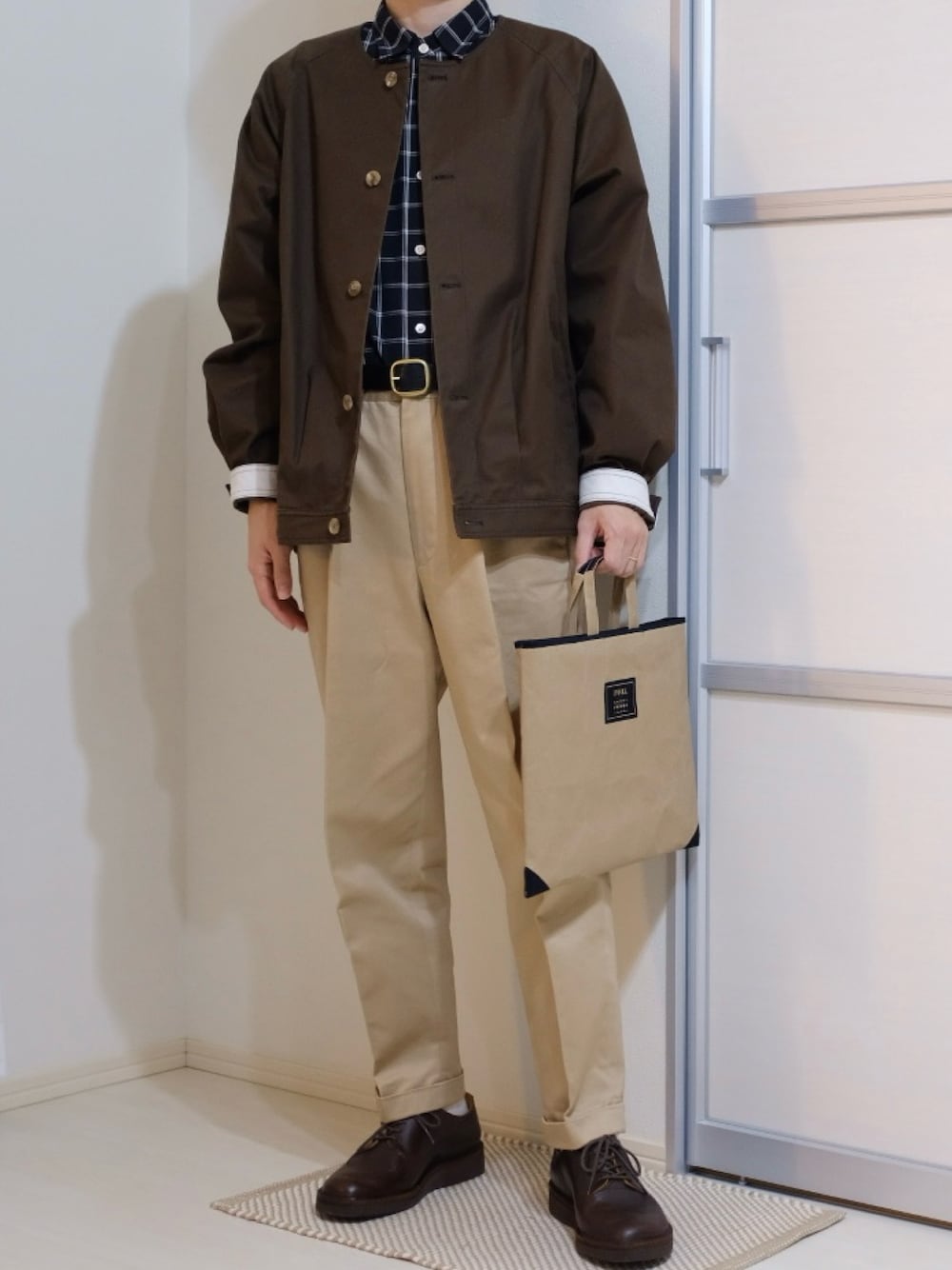 ベージュ系のチノパンツ、ブラック系のシャツ/ブラウス、ブラウン系のブルゾンを着用したメンズの秋コーディネートの1枚目の写真