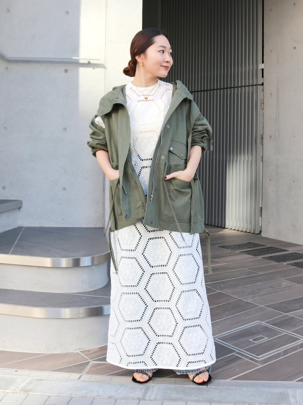 グリーン系のその他アウター、ホワイト系のワンピース、ブルー系のデニムパンツを着用したレディースの冬コーディネートの1枚目の写真