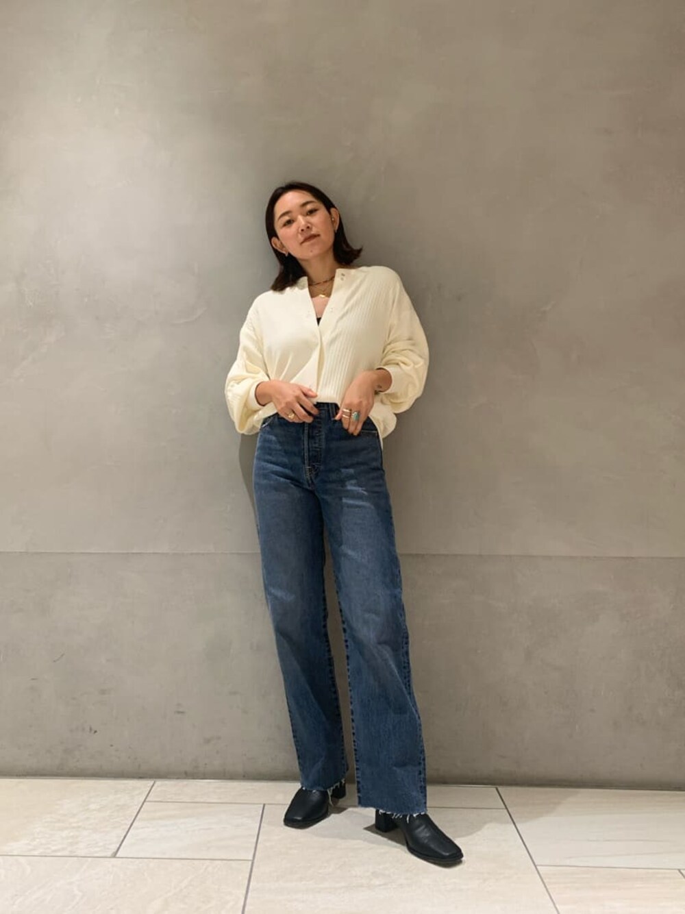 ブラック系のブーツ、ブルー系のデニムパンツ、ホワイト系のカーディガン/ボレロを着用したレディースの秋コーディネートの1枚目の写真