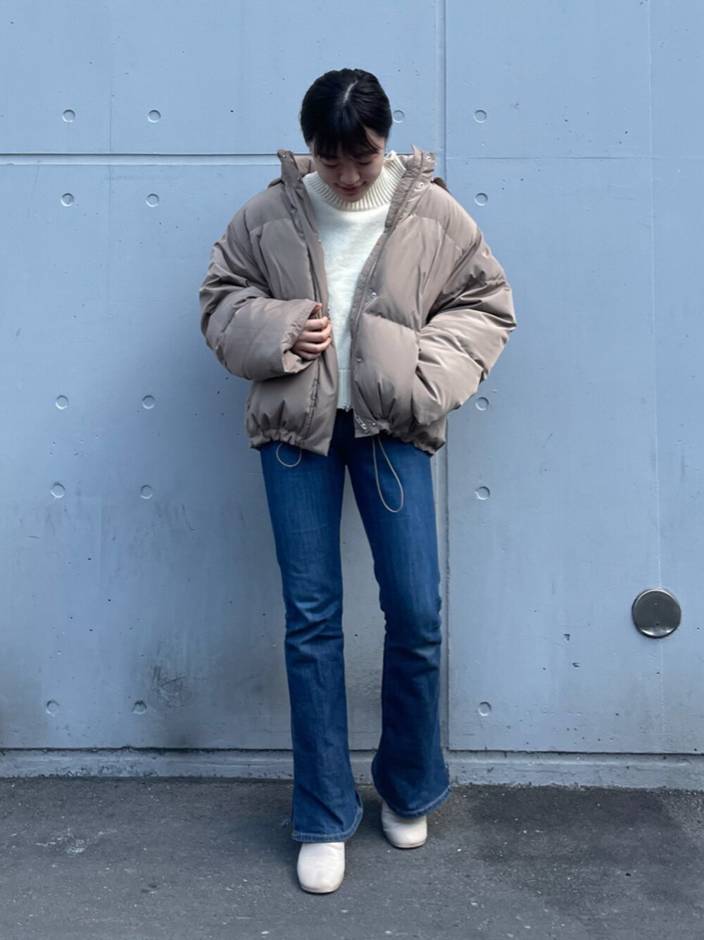 ブルー系のデニムパンツ、ベージュ系のダウンジャケット/コートを着用したレディースの冬コーディネートの1枚目の写真