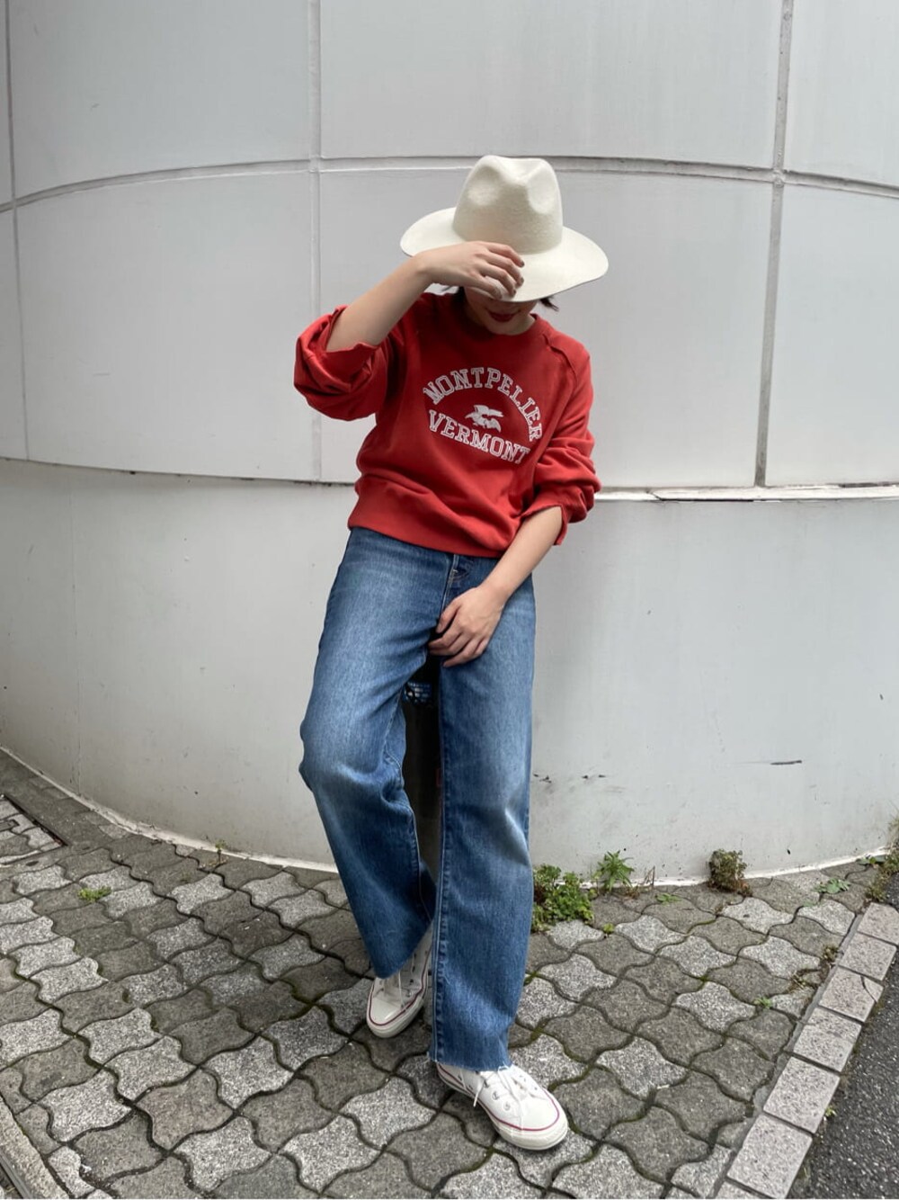 ブルー系のデニムパンツ、レッド系のスウェット、ホワイト系のハットを着用したレディースの夏コーディネートの1枚目の写真