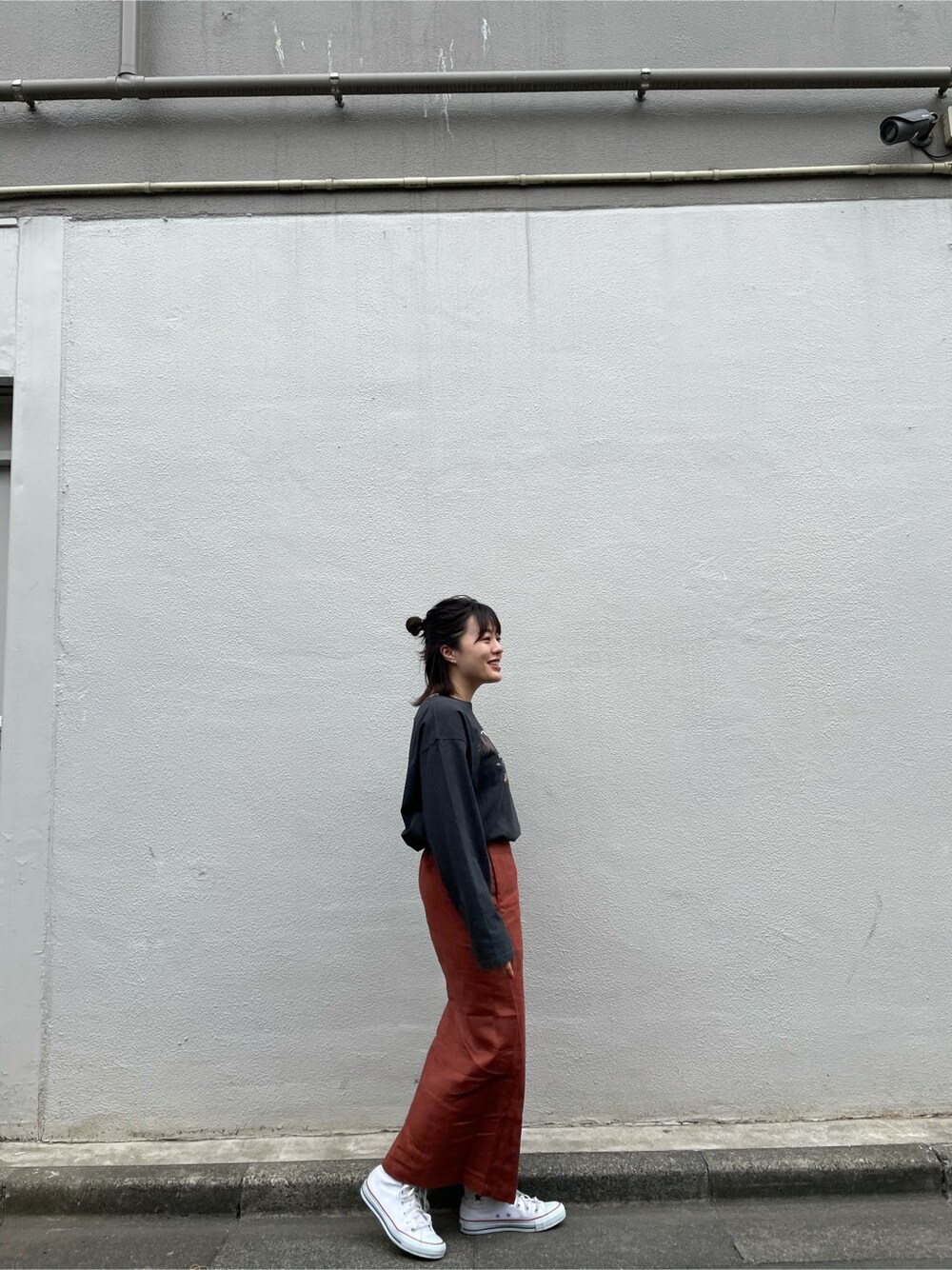 オレンジ系のスカートを着用したレディースの春コーディネートの1枚目の写真