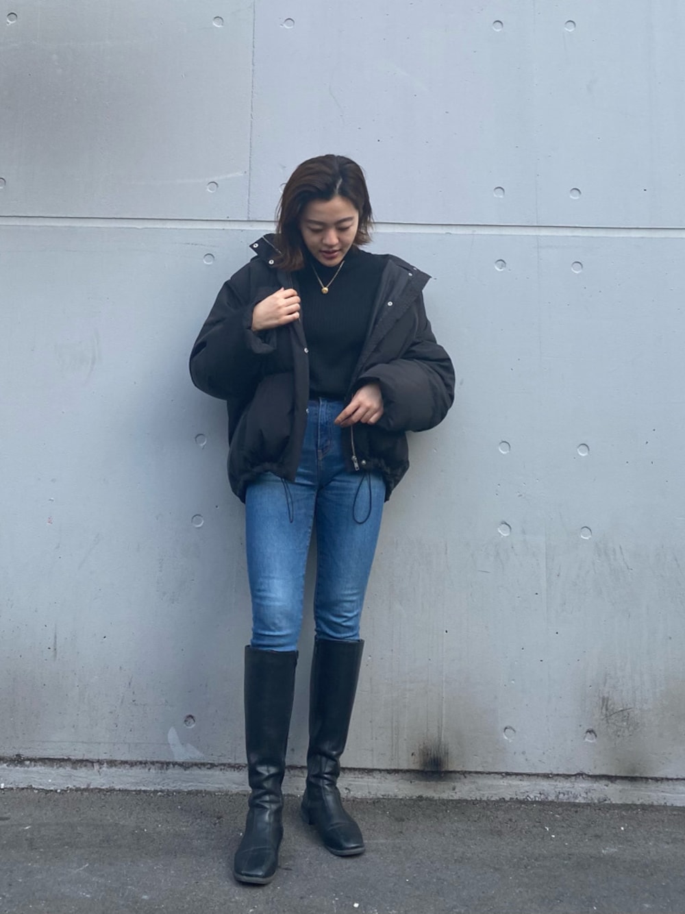 ブルー系のデニムパンツ、ブラック系のダウンジャケット/コートを着用したレディースの冬コーディネートの1枚目の写真