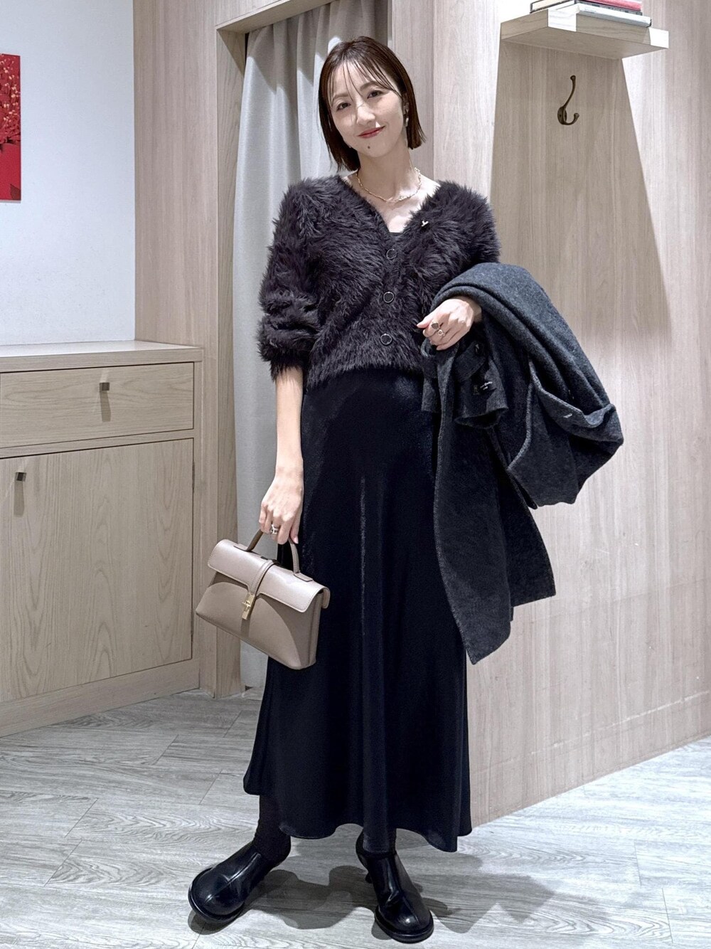 ベージュ系のショルダーバッグ、グレー系のその他アウター、ブラック系のスカートを着用したレディースの冬コーディネートの1枚目の写真